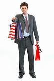 Man in suit stretching hand with shopping bags
