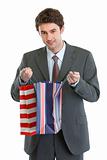 Man in suit looking into shopping bag