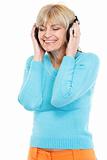 Happy middle age woman listening music in headphones