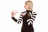 Happy middle age woman pointing on piggy bank