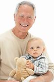 Studio Portrait Of Grandfather Holding Grandson With Teddy Bear