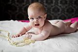 cute little girl infant lying on the rug with pearl beads and we