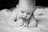 infant girl plays with enthusiasm pearl beads lying on tummy