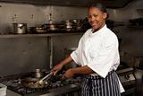 Female Chef Preparing Meal On Cooker In Restaurant Kitchen