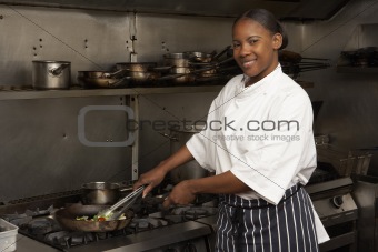 Female Chef Preparing Meal On Cooker In Restaurant Kitchen