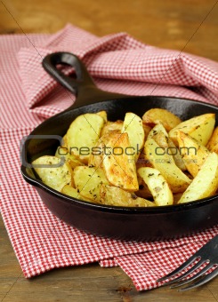 fresh potatoes fried in a pan on a wooden table