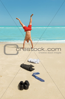 businessman doing handstand on the beach