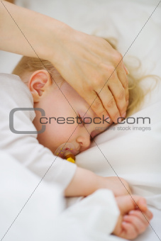 Closeup on mother checking temperature of forehead of baby