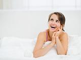 Smiling woman laying in bed and looking on copy space