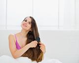 Dreaming woman combing gorgeous long hair