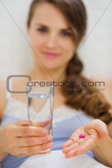 Closeup on pills and glass of water in hand of happy woman