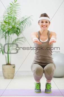 Smiling woman in sports wear squatting