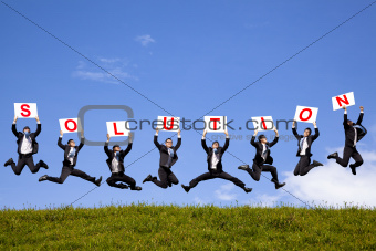 happy businessman holding solution text and jumping on the green field