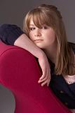 Thoughtful Teenage Girl Relaxing On Chaise Longue