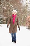 Senior Woman Walking Through Snowy Woodland