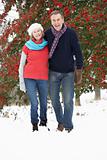 Senior Couple Walking Through Snowy Woodland