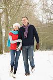Senior Couple Walking Through Snowy Woodland