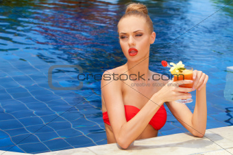 Beautiful blonde in a pool with a cocktail