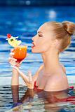 Pretty girl sipping a tropical drink in a pool