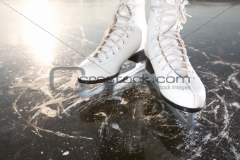 Wide skates on ice with sun reflected in behind