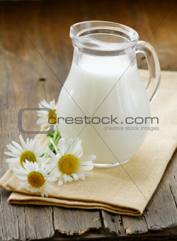 pitcher of milk on a wooden table wish  daisy , rustic still life