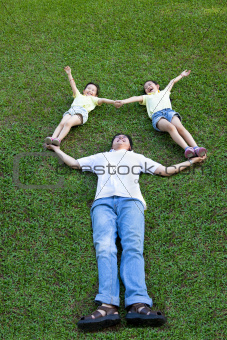 happy asian family lying and playing on the grass