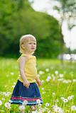 Baby girl on dandelions field looking on copy space