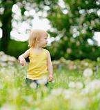 Baby girl on dandelions field looking back