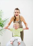 Mother mother holding baby sitting on fitness ball