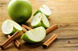 green apples and cinnamon sticks on a wooden background