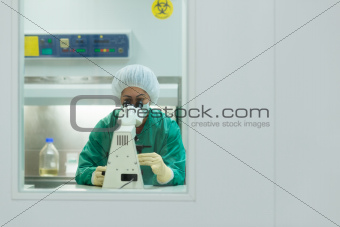 Woman at work with microscope in biotechnology laboratory
