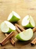 green apples and cinnamon sticks on a wooden background