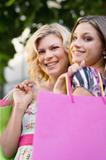 Two female friends smiling with shopping bags
