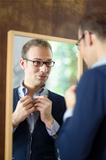 Young man dressing up and looking at mirror