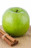 Ripe green apple with cinnamon sticks