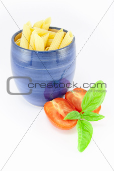 Pens pasta in a blue jar with tomatoes and basil
