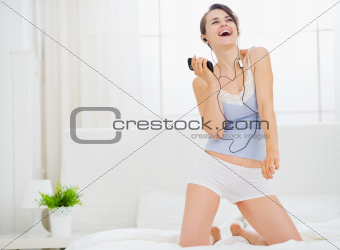 Girl listening music and dancing on bed