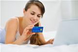 Happy woman laying on bed with laptop and shopping on net