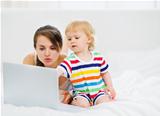 Baby showing something to mother in laptop