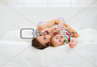Mother playing with baby in bed