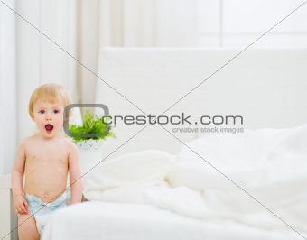 Portrait of surprised baby in bedroom
