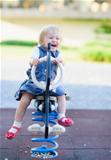 Happy baby swinging on horse on playground