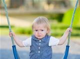 Portrait of unhappy baby sitting on swing