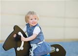 Baby swing on horse on playground and looking on copy space