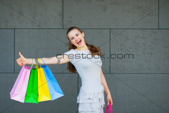 Smiling woman with shopping bags showing thumbs up