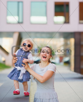 Smiling mother playing with baby in city