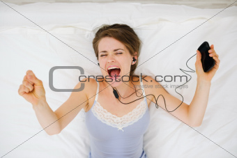 Portrait of girl laying on bed and listening music. Upper view
