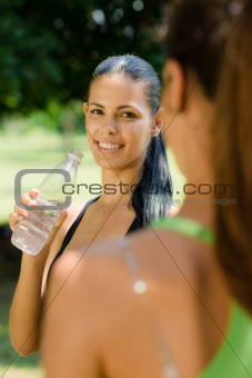 Two young women relaxing after fitness in park