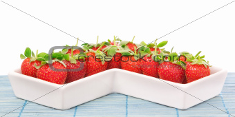 Red Strawberries in a porcelain dish. Closeup. On a white backgr
