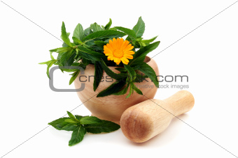 Mint leaves and Calendula in a wooden mortar.